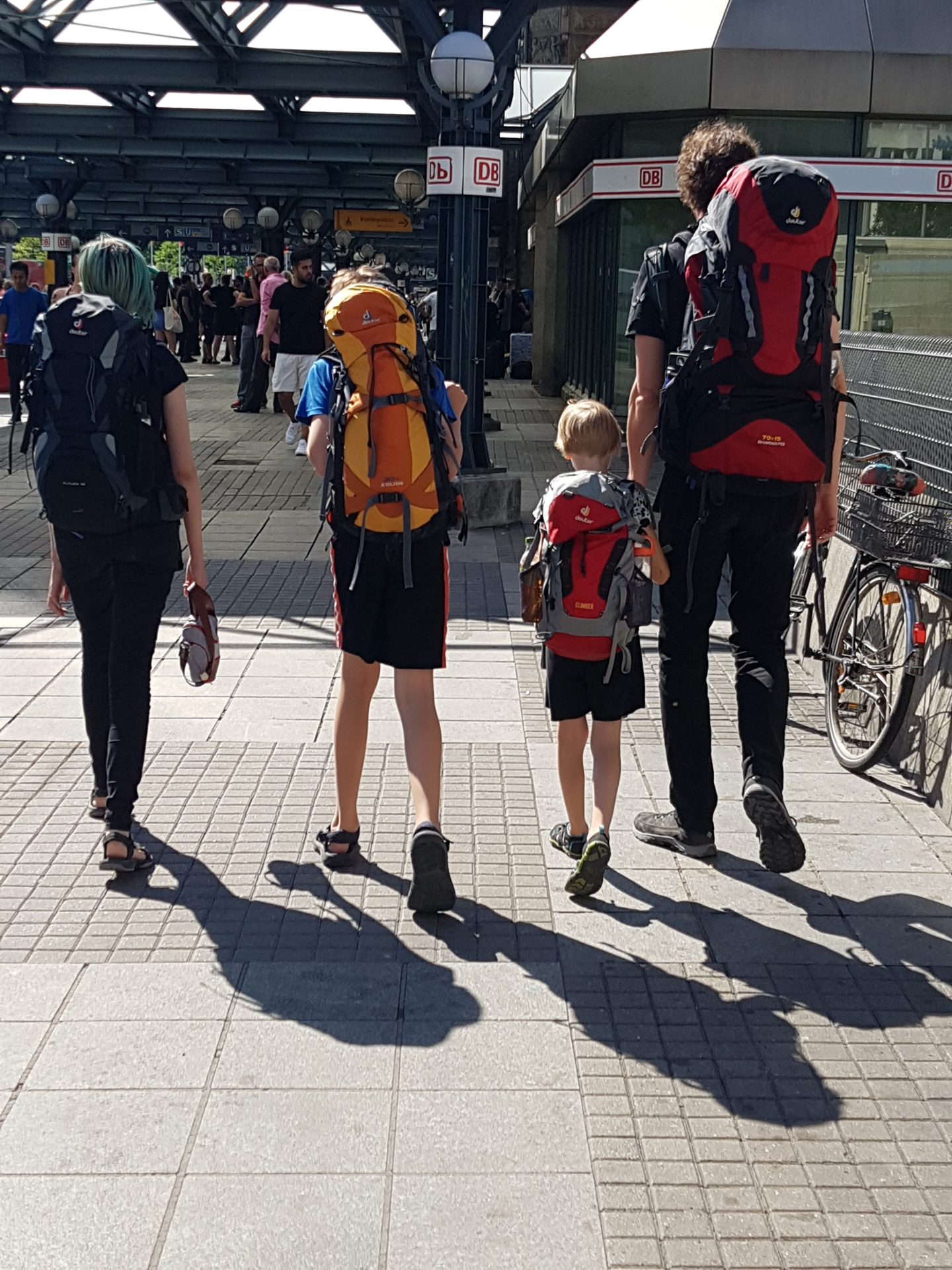 Ein Vater und seine drei Kinder, alle mit Rucksäcken bepackt, laufen in den Hamburger Bahnhof